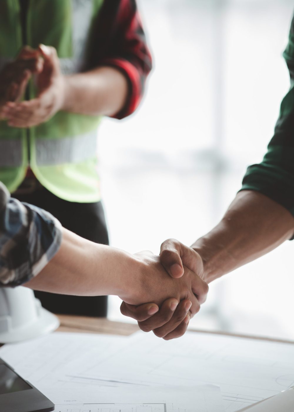 Team engineers and architects shake hands with the condo project owners after the meeting to present room plans and details of the condo building structure. Concept of building design and construction